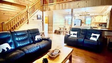 A spacious living area with two leather sofas, a wooden coffee table, and a staircase leading to an upper level.
