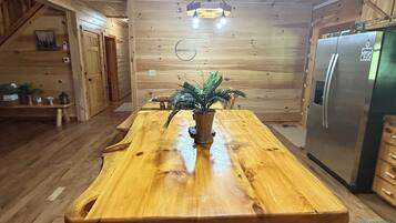 A wooden interior with a central island, a refrigerator, and a hanging light fixture.