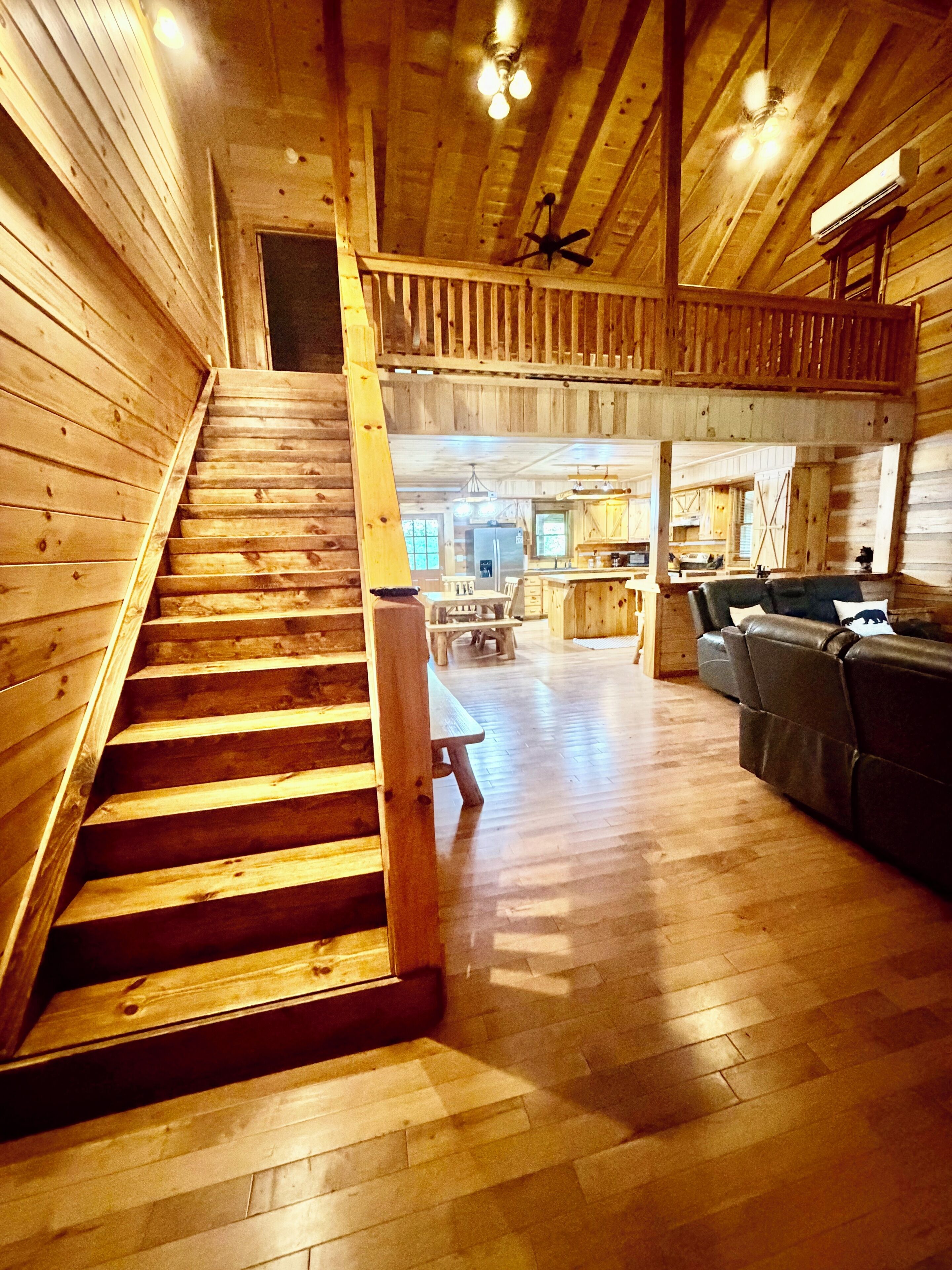 Un intérieur en bois avec un escalier menant à un deuxième étage, un coin repas et un espace salon avec un canapé.