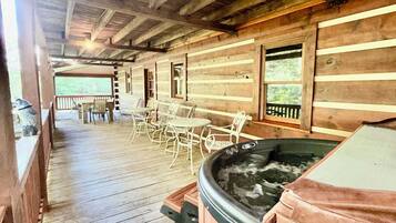 A wooden deck with a hot tub, outdoor seating, and a view of the outdoors.