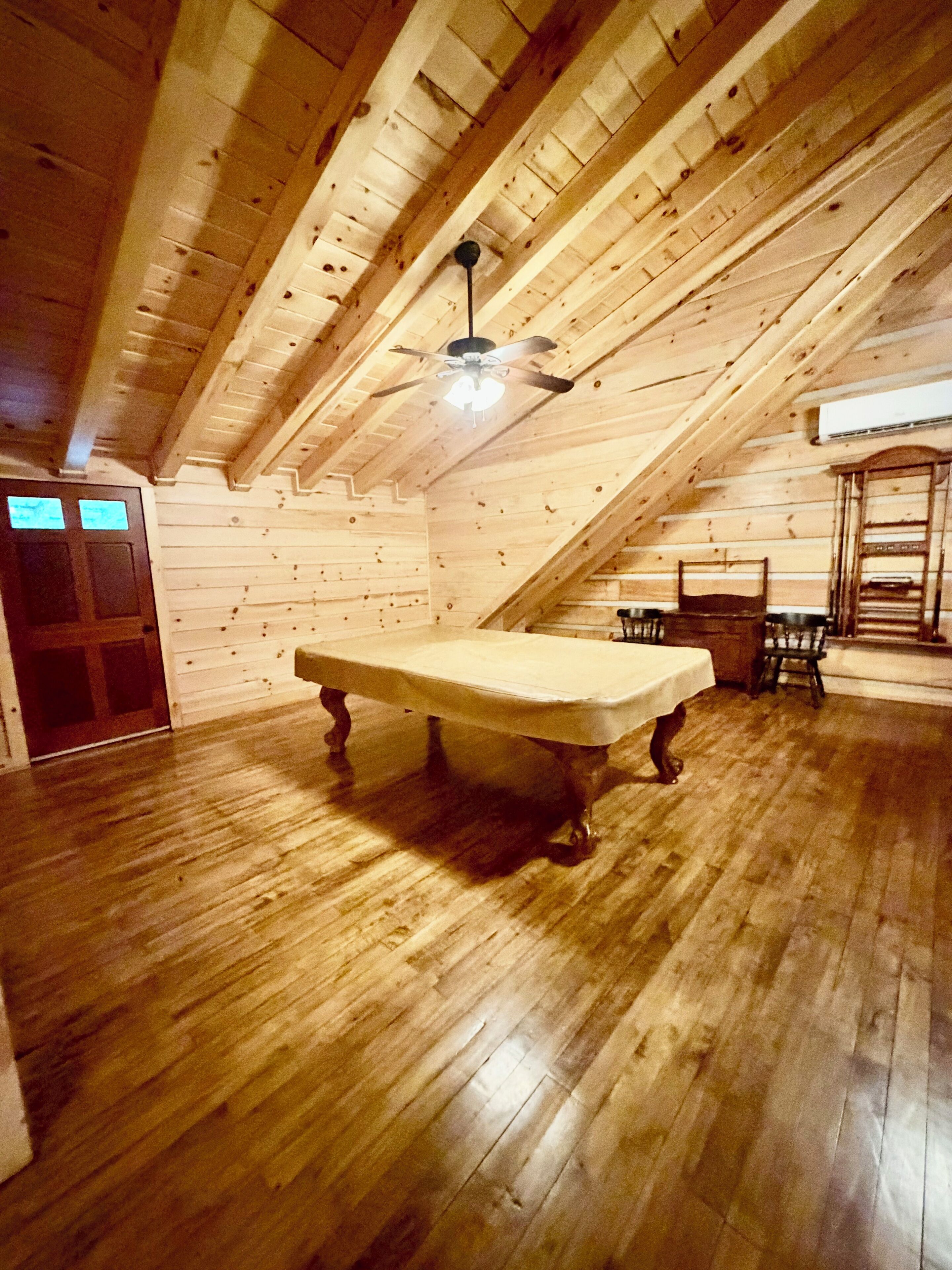 Ein Zimmer mit Holzboden, einem Tisch und einem Deckenventilator.