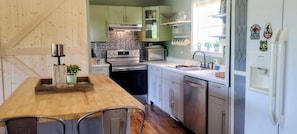 A modern kitchen with a wooden dining table, stainless steel appliances, and a refrigerator with magnets.
