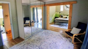 A room with a large sliding glass door leading to a balcony, a bed with a green wall, a chair, and a ceiling fan. - Sunrise over the lake and mountains...  (Albemarle)
