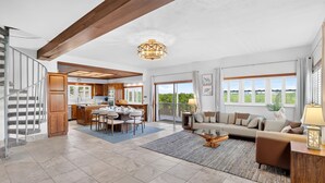 A spacious living area with a dining table, sofa, and a staircase. - Bayside - Islamorada Waterfront, 360 Viewing Deck, Htd Swim Spa (Islamorada)