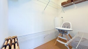 A room with a white wall, a metal shelf unit, a baby changing station, and a baby seat. - Bayside - Islamorada Waterfront, 360 Viewing Deck, Htd Swim Spa (Islamorada)