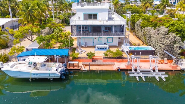 A two-story house with a balcony, a hot tub, and a boat docked in the water. - Bayside - Islamorada Waterfront, 360 Viewing Deck, Htd Swim Spa (Islamorada)