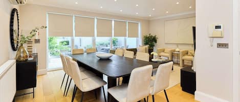 A modern dining area with a large table, chairs, and a view of the outdoors.