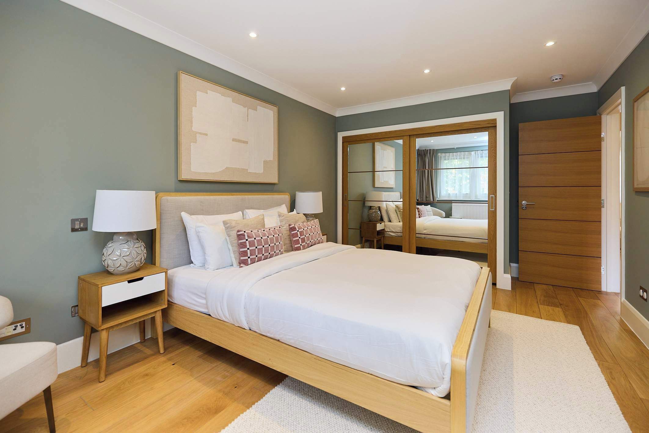 A bedroom with a bed, bedside tables, a mirror, and a wardrobe.