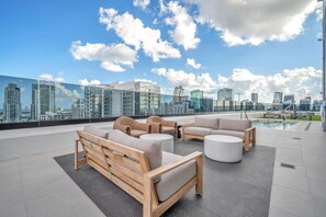 A rooftop terrace with outdoor seating, a pool, and a city skyline view. - District 225 - Brand New Downtown Apartment (Miami)
