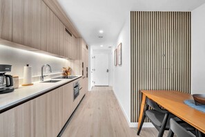 Une cuisine moderne avec des meubles en bois, un four encastré et une machine à café.