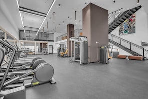 A gym with cardio equipment, weight machines, and a staircase. - District 225 - Brand New Downtown Apartment (Miami)