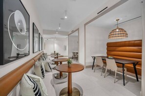 A modern interior with round tables, a sofa, and a hanging light fixture. - District 225 - Brand New Downtown Apartment (Miami)