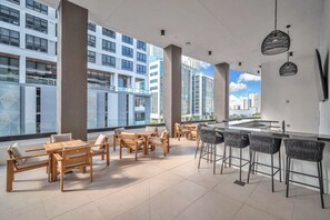 A rooftop bar with outdoor seating, large windows, and a city view. - District 225 - Brand New Downtown Apartment (Miami)