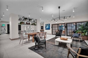 A modern hotel lobby with a dining area, a reception desk, and a large window offering a view. - District 225 - Brand New Downtown Apartment (Miami)