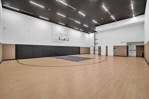 A basketball court with a wooden floor, a basketball hoop, and a wall-mounted rack. - District 225 - Brand New Downtown Apartment (Miami)