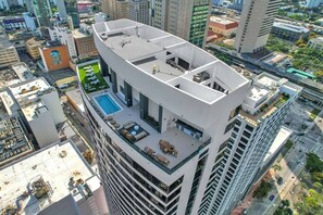 Un immeuble de grande hauteur doté d’une piscine sur le toit et d’un espace extérieur aménagé pour s’asseoir.
