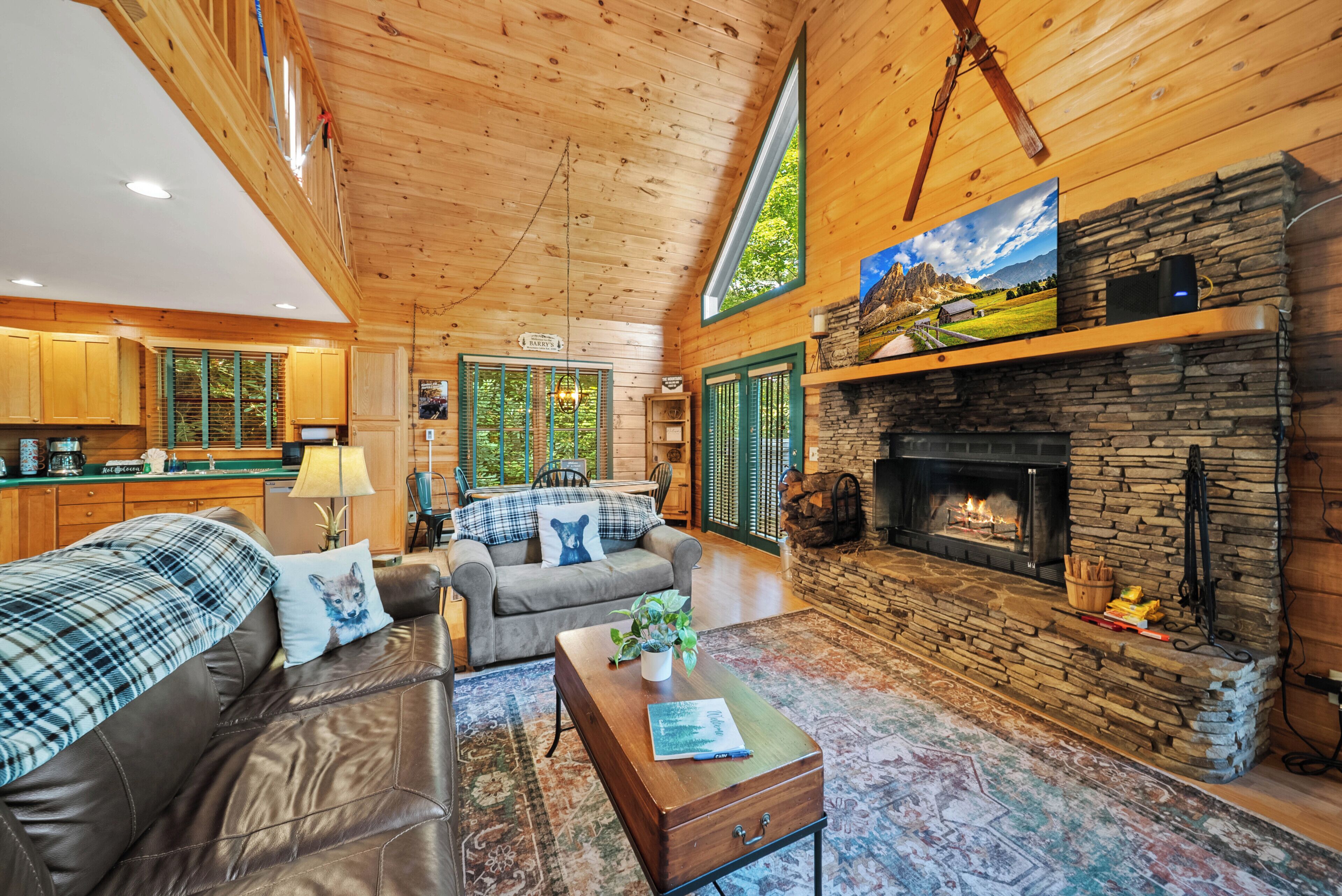 A cozy cabin interior with a fireplace, wooden walls, and a dining area.