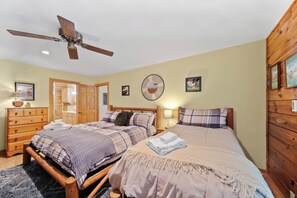 A bedroom with two beds, a wooden wardrobe, a ceiling fan, and wall decorations. - Cozy A-Frame Steps from Downtown Banner Elk (Banner Elk)