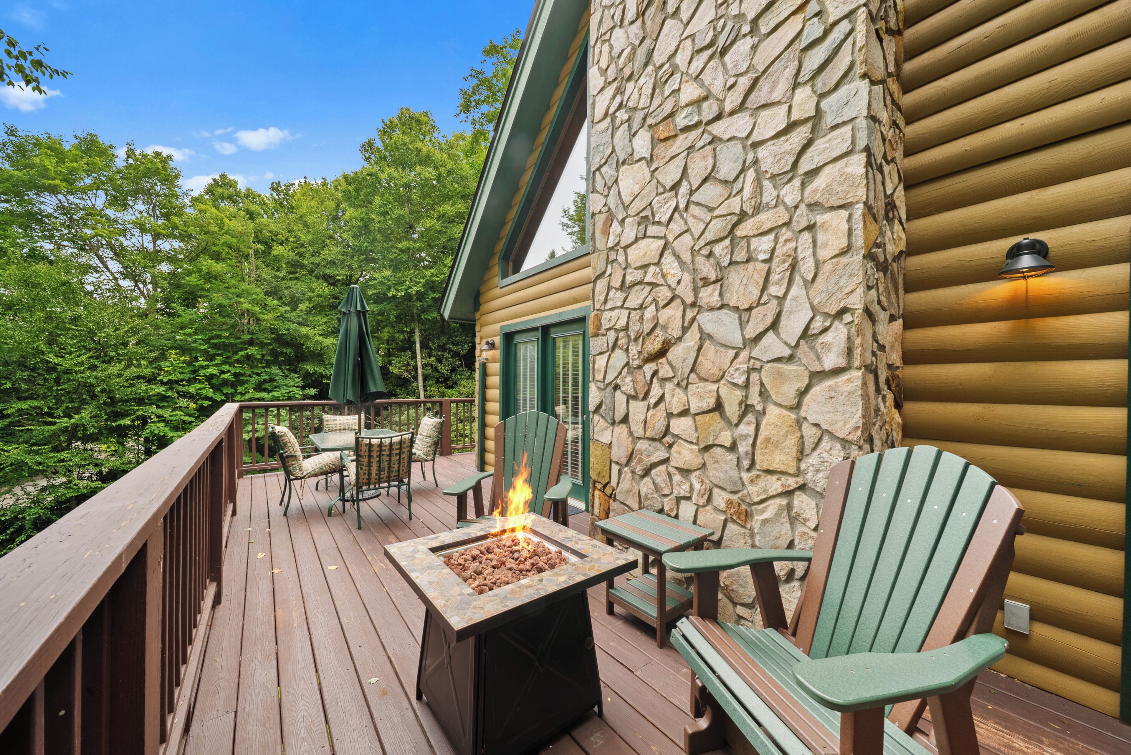 A deck with a stone wall, outdoor furniture, and a fire feature.