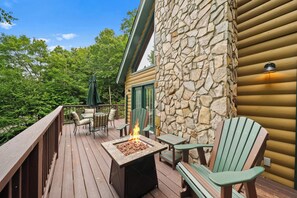 A deck with a stone wall, outdoor furniture, and a fire feature. - Cozy A-Frame Steps from Downtown Banner Elk (Banner Elk)