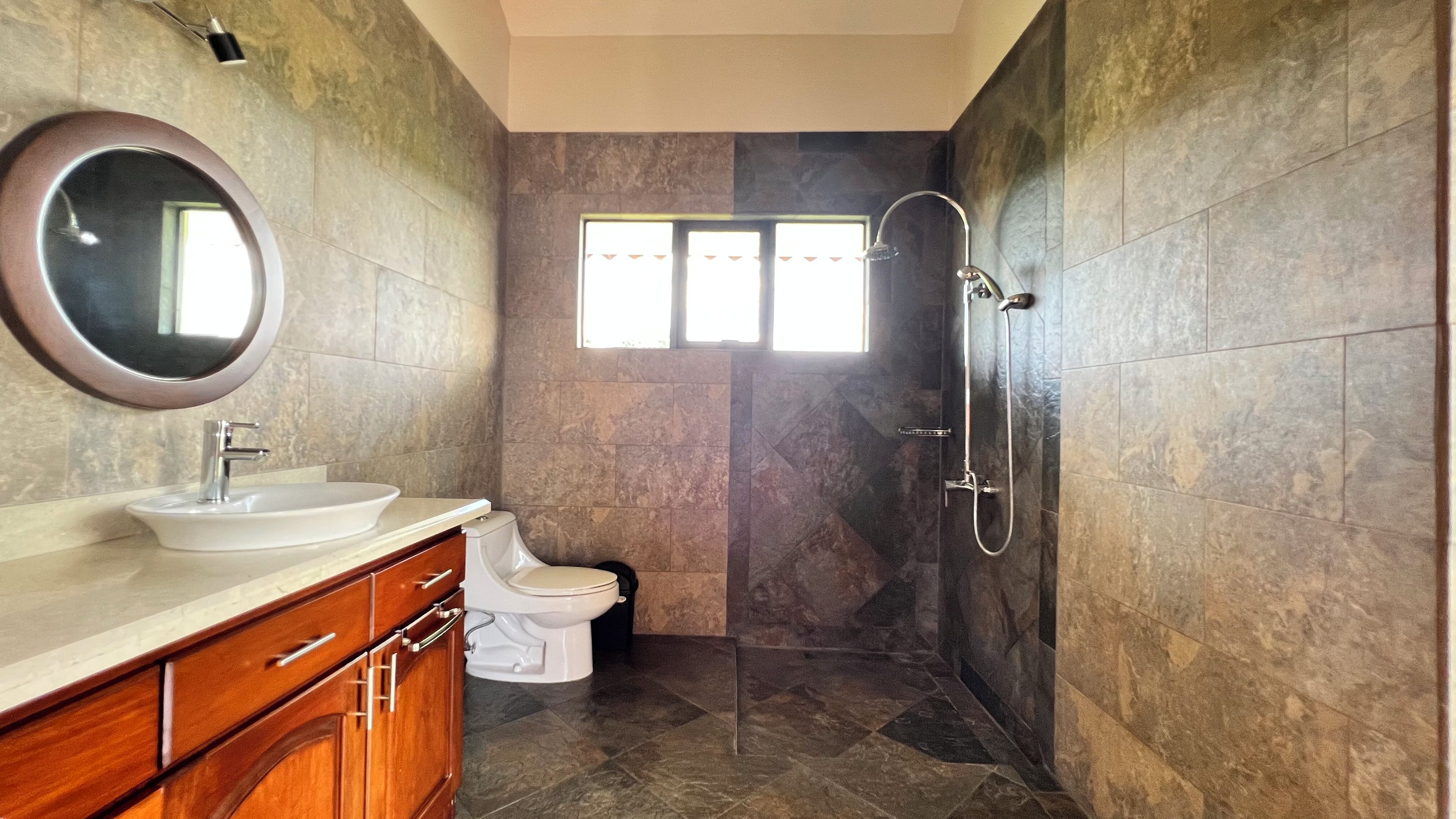 Une salle de bain équipée d’un lavabo, d’un miroir, de toilettes et d’une douche.