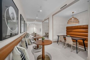 Ein modernes Interieur mit runden Tischen, einer Sitzecke mit einer Bank und einem großen Spiegel.