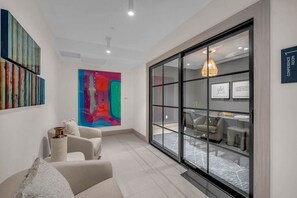 Ein modernes Interieur mit einem großen, abstrakten Gemälde, einer Sitzecke mit Sofa und Sesseln sowie einem Blick in einen Konferenzraum durch eine Glastrennwand.