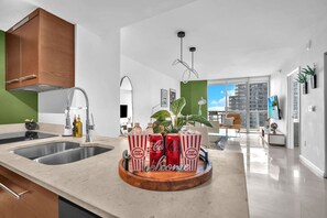 A modern kitchen with a central island, a dining area with a view, and a living space with a large window. - Basquiat Brickell Luxury Retreat (Miami)