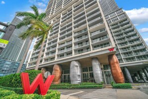A high-rise building with a modern architectural design, featuring a prominent 'W' sign at the entrance, large columns, and a clear view of the surrounding urban skyline. - Basquiat Brickell Luxury Retreat (Miami)