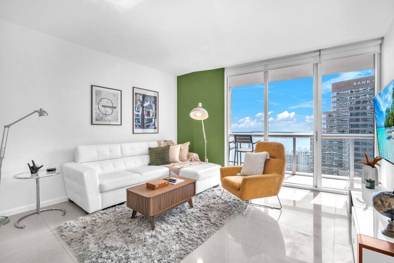 A modern living room with a white sofa, a round coffee table, and a green accent wall.