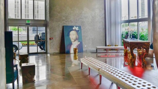 Eine geräumige Lobby mit einem großen Fenster, einer Bank und einem Gemälde an der Wand.