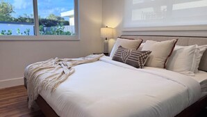 Quarto com uma cama grande, abajur e vista para o exterior.