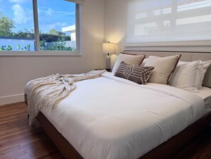 Ein Schlafzimmer mit einem großen Bett, einer Nachttischlampe und Blick ins Freie.