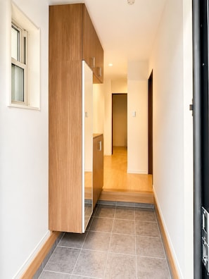 Ein Flur mit einem Holzkasten, einem Fenster und einer Tür zu einem anderen Raum.