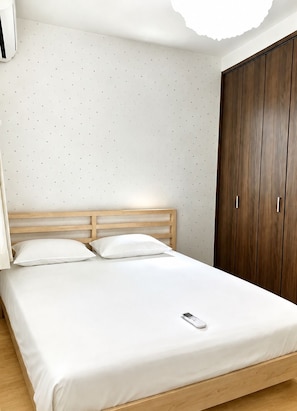 Ein Schlafzimmer mit einem Bett, einem hölzernen Kopfteil, weißer Bettwäsche, einem Kleiderschrank und einer Wand mit Sternenmuster.