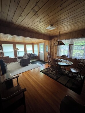 A cabin interior with a dining area, seating, and a view of the outdoors.