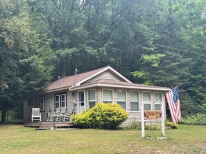 A small, single-story building with a porch and a sign indicating it is a country cottage. - 2 Bedroom cabin in the heart of the Hiawatha National Forest... (Manistique)