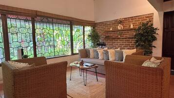 A living room with a sofa, two armchairs, a coffee table, and a large window with a view of greenery.