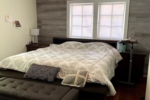 Ein Schlafzimmer mit Bett, Nachttischen, einer Lampe und einem Fenster.