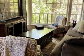 Un salon comprenant un téléviseur, une table basse, un fauteuil à motifs et un canapé.