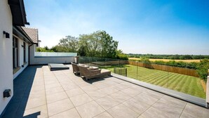 A spacious balcony with a clear view of a well-maintained lawn and distant fields. - Luxurious Villa Retreat in Wilmslow (Wilmslow)