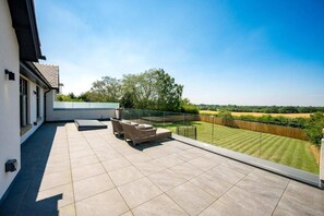 A spacious balcony with a clear view of a well-maintained lawn and distant fields.