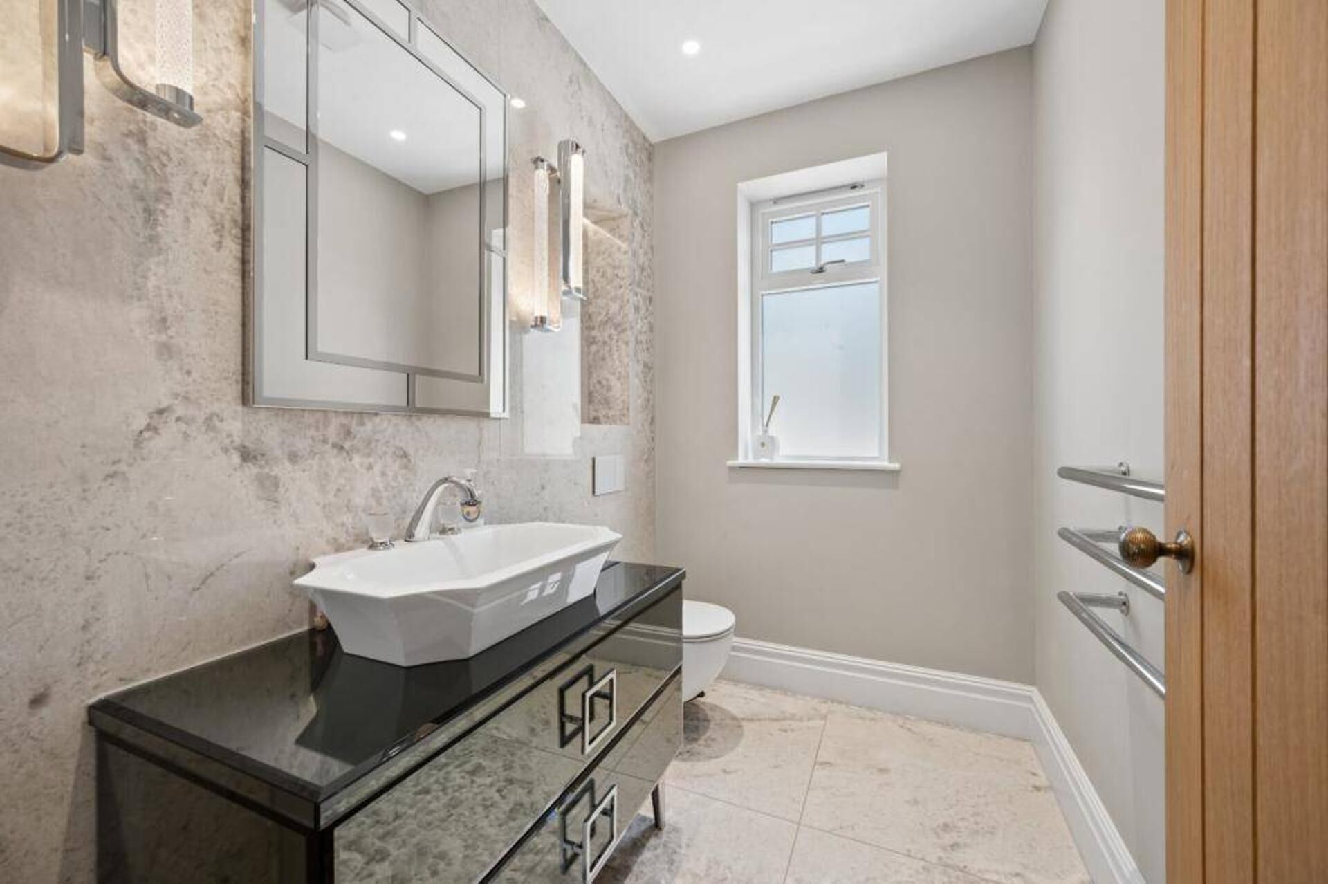 A bathroom with a white sink, a mirror, a toilet, and a window.