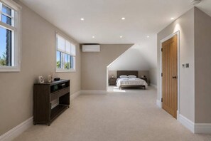 A bedroom with a sloped ceiling, a bed, a nightstand, and a dresser.