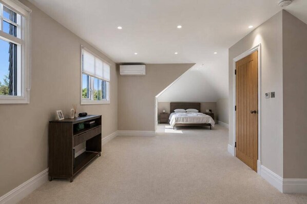 Un dormitorio con techo inclinado, una cama, una mesita de noche y un aparador.