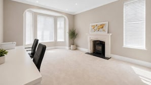 A conference room with a fireplace, a dining table, and two large windows with blinds. - Luxurious Villa Retreat in Wilmslow (Wilmslow)