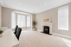 A conference room with a fireplace, a dining table, and two large windows with blinds.