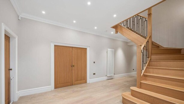 A spacious room with a wooden staircase and a radiator. - Luxurious Villa Retreat in Wilmslow (Wilmslow)