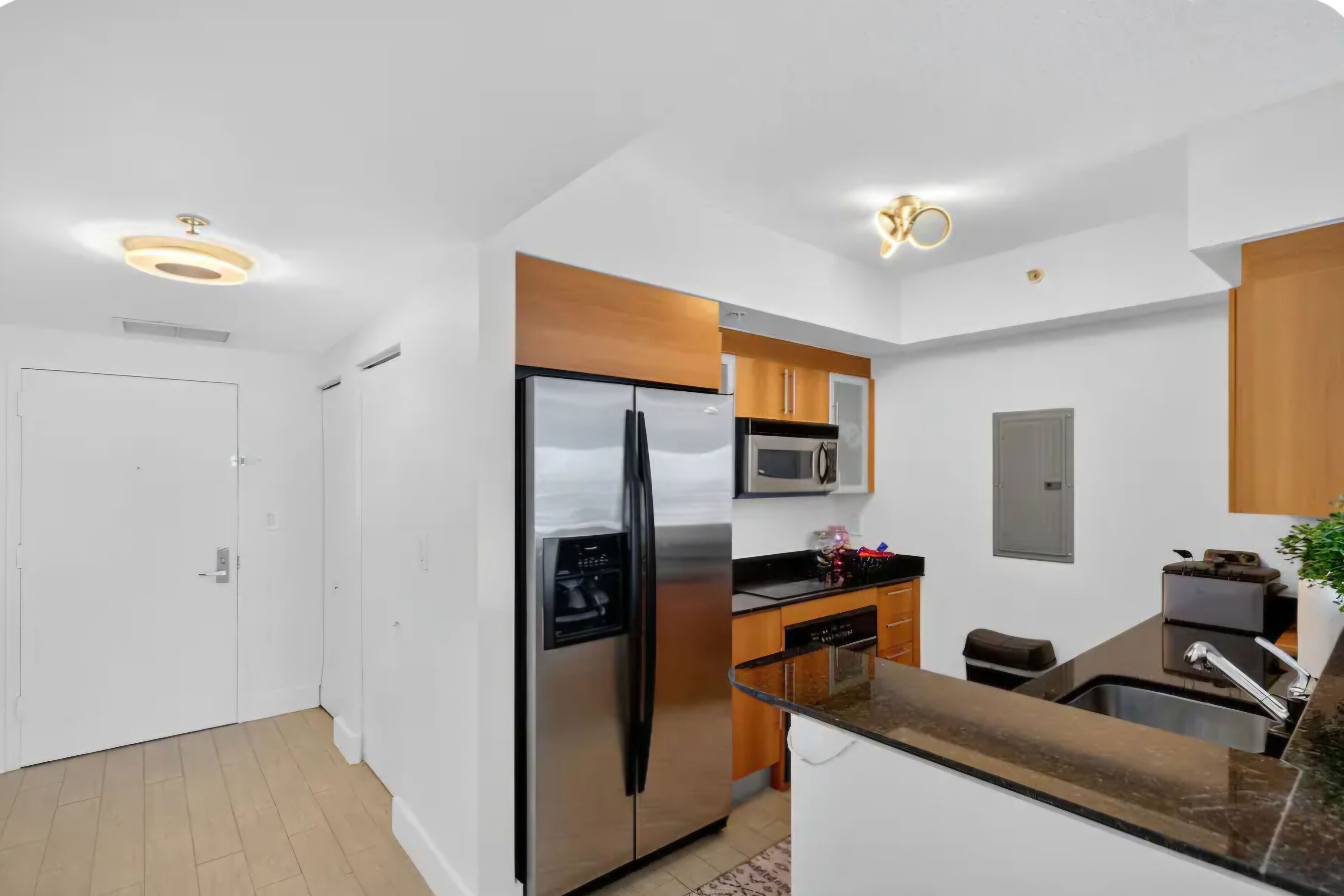 A modern kitchen with stainless steel appliances, wooden cabinets, and a built-in microwave.