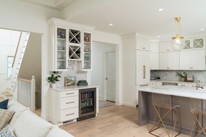 A modern kitchen with white cabinetry, a built-in wine cooler, and a bar area with stools. - 5 Bedroom house with pool half mile from track and SPAC and a mile to Broadway (Saratoga Springs)